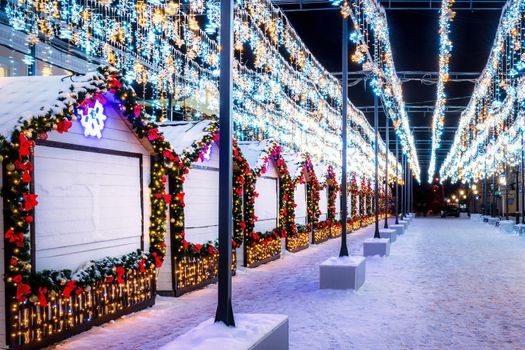 Christmas or New Year's market in a European city with houses decorated with toy balls and garlands at night.