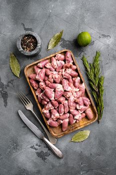 Raw uncooked chicken gizzards, chicken hearts set, on gray stone table background, top view flat lay