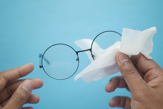 cleaning eyeglass with tissue close up .