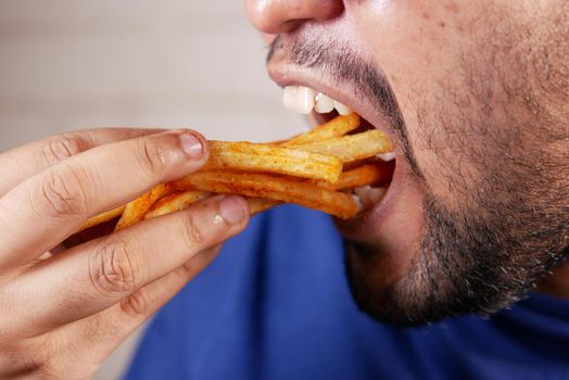 a fat man eating french fries while sited .