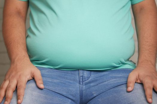 fat man with a big belly while sitting on a chair .