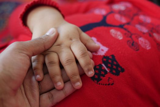 father holding hand of baby child, close up