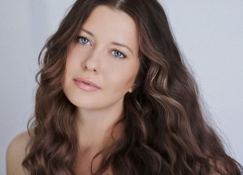 Hairstyle model and beauty face closeup. Beautiful woman with long straight brown hair styled in curly waves, classic glamour style and luxury fashion portrait.