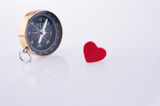 Compass near a Red heart on a white background