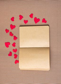 Paper hearts around notebook on cardboard