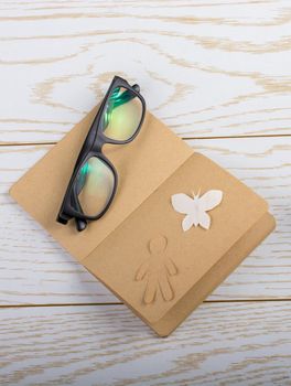 Blank notebook, white paper butterfly, paper man and sun glasses