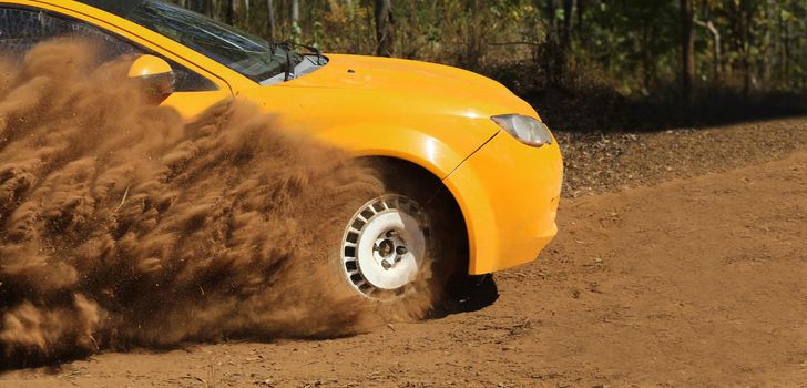 Rally race car drifting on dirt track.