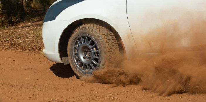 Rally race car drifting on dirt track.