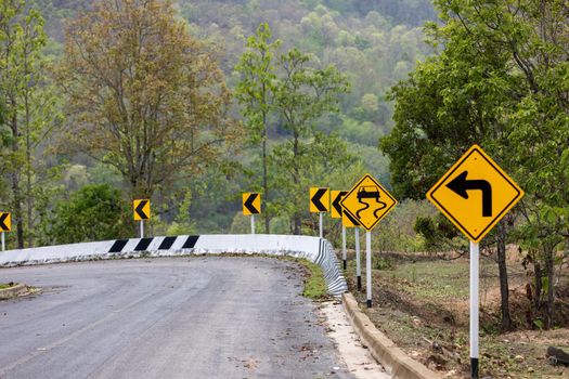 Road sign  caution indicating left turn and danger of  slippery road on mountain