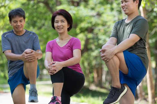 Father mother and adult son exercise in the park