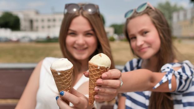 Two girls are presenting ice cream to the viewer