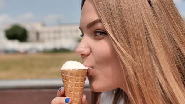 The girl eats an ice cream cone on the street of the city