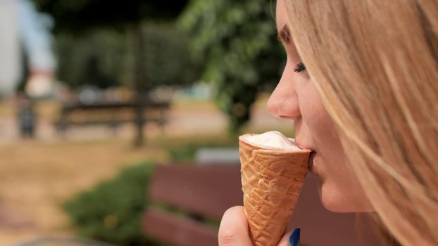 The girl eats an ice cream cone on the street of the city