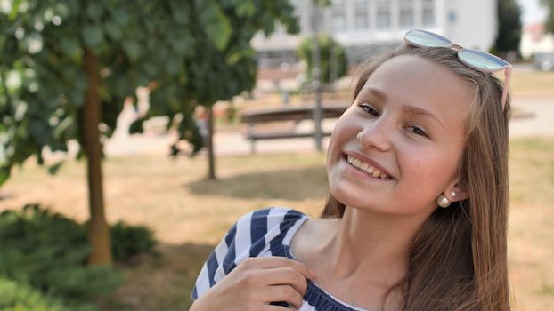 Portrait of a young smiling girl in the park on a summer day