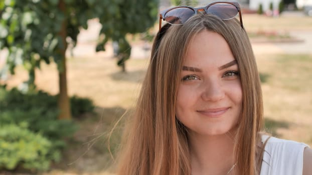 Portrait of a young smiling girl in the park on a summer day
