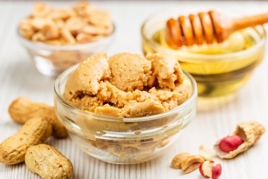 Close up of Peanut butter in a glass bowl with honey on the background