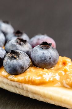 Healthy appetizers close up with sliced bananas with peanut butter spread and blueberries on the top
