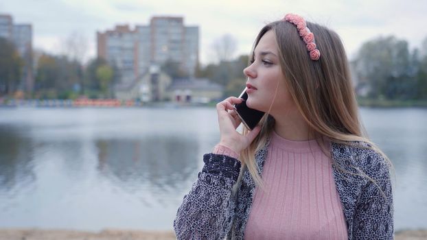 The girl is talking on the phone in the autumn evening