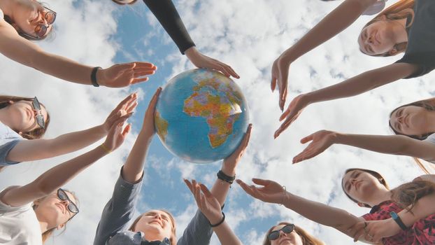 Earth conservation concept. 11 girls hug the earth globe with their hands