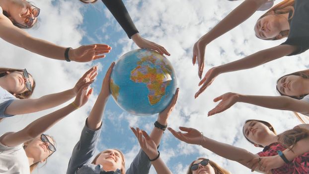 Earth conservation concept. 11 girls hug the earth globe with their hands