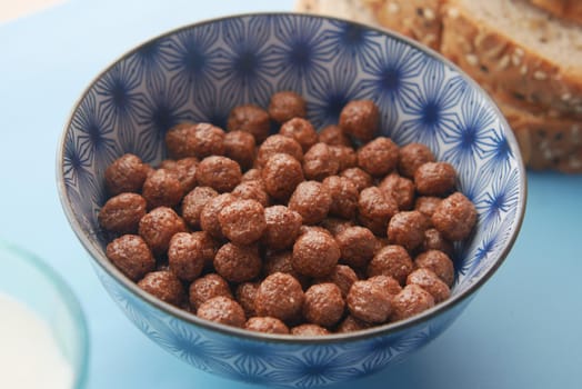Top view of chocolate corn flakes in a bowl on pink .