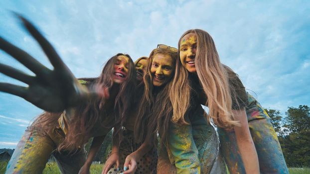 Cheerful girls posing smeared in multi-colored powder