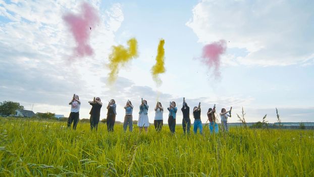 Cheerful girls shoot colorful powder from pneumatic clappers