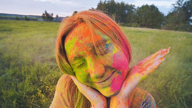 Cheerful girl posing smeared in multi-colored powder. Close-up face