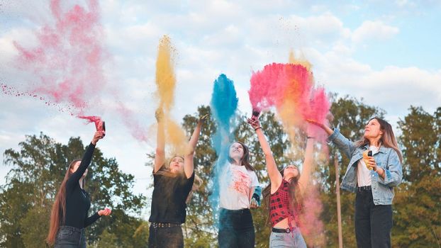 Cheerful girls toss up multi-colored powder. Holi holiday