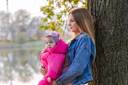 Young mother with her baby on a warm autumn day in the fresh air