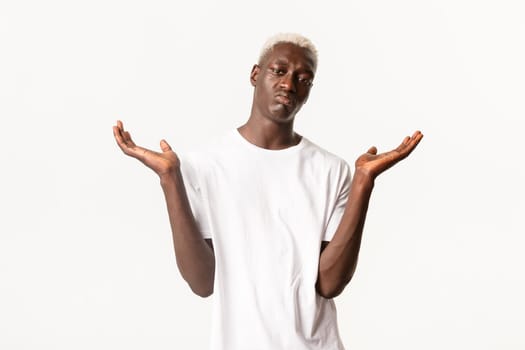 Portrait of indifferent african-american blond man, shrugging and spread hands sideways clueless, standing white background.
