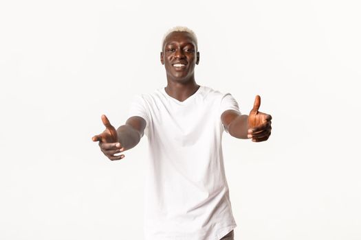 Portrait of friendly handsome african-american blond man, reaching hands to hold something, hugging you, standing white background.