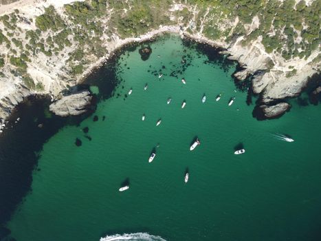 Sea landscape with rocky coastline on sunset time with cloudy sky. Yachts in the Sea on a background of rocky shores. The concept of perfect place for summer travel and rest.