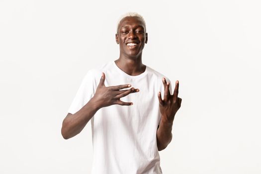 Cool and sassy african-american blond guy, showing west coast hand signs and smiling broadly, standing white background.