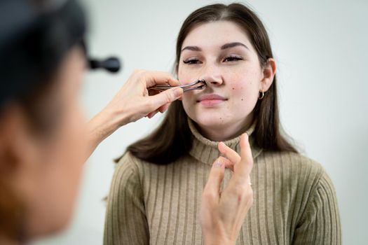 Professional female doctor otorhinolaryngologist doing nose examination with otoscope in modern hospital. Nasal congestion, sinusitis, allergy concept. Woman ENT doctor and patient in office clinics.