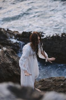 a woman in a white dress stands on the stones by the ocean nature travel. High quality photo