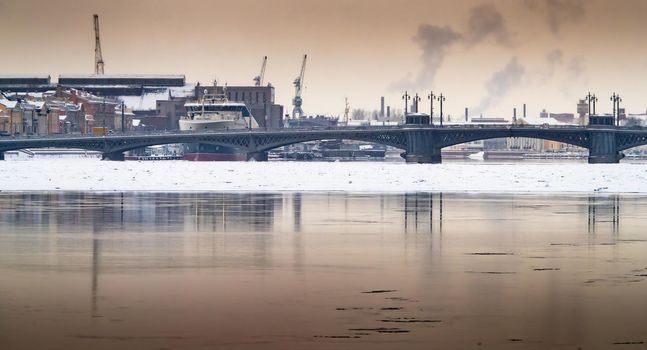 The panoramic image of the winter city Saint-Petersburg with picturesque reflection on water at sunset, big ship moored near Blagoveshchensky bridge, English embankment. High quality photo