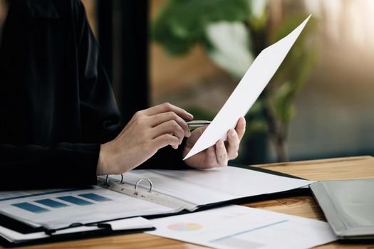 Businesswoman holding a pen pointing to budget documents to check investments