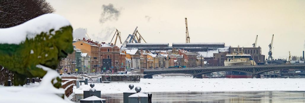 The panoramic image of the winter city Saint-Petersburg with picturesque reflection on water at sunset, big ship moored near Blagoveshchensky bridge, English embankment. High quality photo