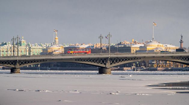 The panoramic view of the winter city Saint-Petersburg, frozen Neva river, the red touristic bus on Blagoveshchensky bridge, Winter Palace, Admiralty building, Alexander column on background. High quality photo