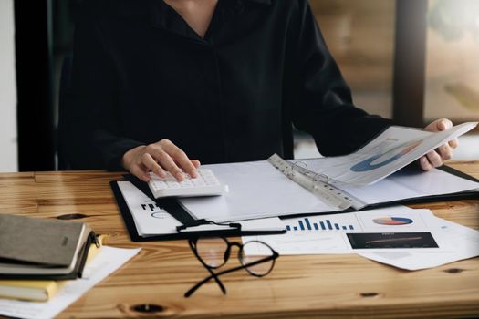 businesswoman working on desk office with using a calculator to calculate the numbers, finance accounting concept