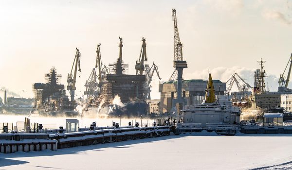The construction of nuclear icebreakers, cranes of of the Baltic shipyard in a frosty winter day, steam over the Neva river, smooth surface of the river. High quality photo