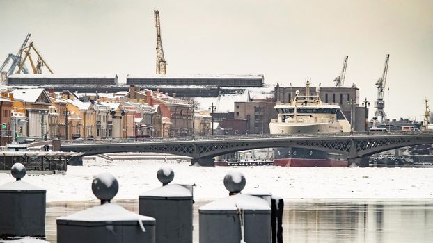 The panoramic image of the winter city Saint-Petersburg with picturesque reflection on water at sunset, big ship moored near Blagoveshchensky bridge, English embankment. High quality photo