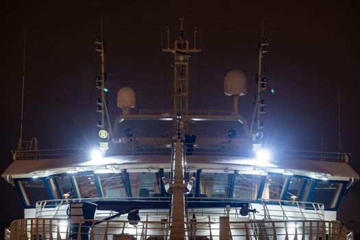 Night close-up of the cockpit of a huge ship with night illumination, fishing trawler, radar equipment at the top. High quality photo
