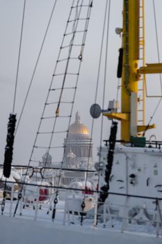 The golden dome of Isaac cathedral through old moored sail boat at frosty day, Winter landscape of St. Petersburg. High quality photo