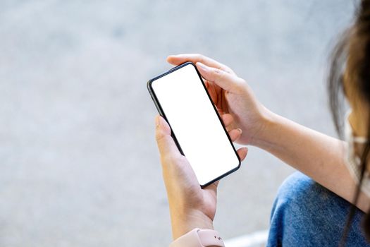 A woman holding a cell phone with a blank white screen. The blank space on the white screen can be used to write a message or place an image