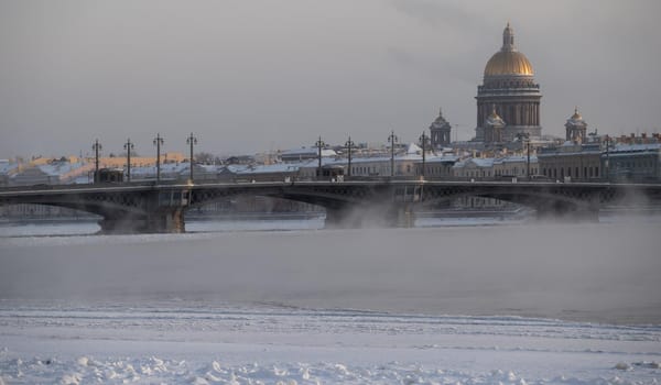 Winter panoramic view of St. Petersburg at frosty day, Isaac cathedral and Blagoveshenskiy bridge on background, steam over frozen Neva river. High quality photo