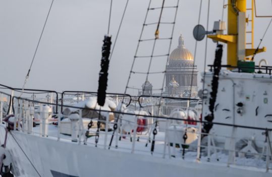 The golden dome of Isaac cathedral through old moored sail boat at frosty day, Winter landscape of St. Petersburg. High quality photo