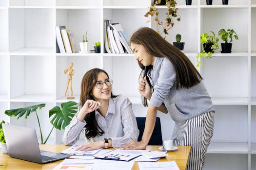 A businesswoman and a colleague are using computers to calculate the last quarter of the year's income budget to plan financial investments for the next year