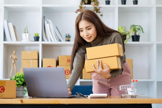 Work from home. happy women selling products online Start a small business owner by using laptop computer to calculate prices and prepare for postage